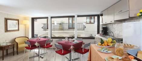 A modern kitchen with a dining area, large windows, and a balcony.