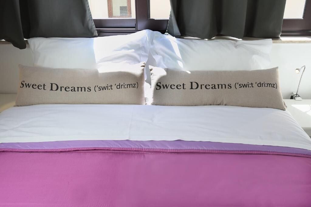 A bed with two pillows labeled "Sweet Dreams" and a purple bedspread.
