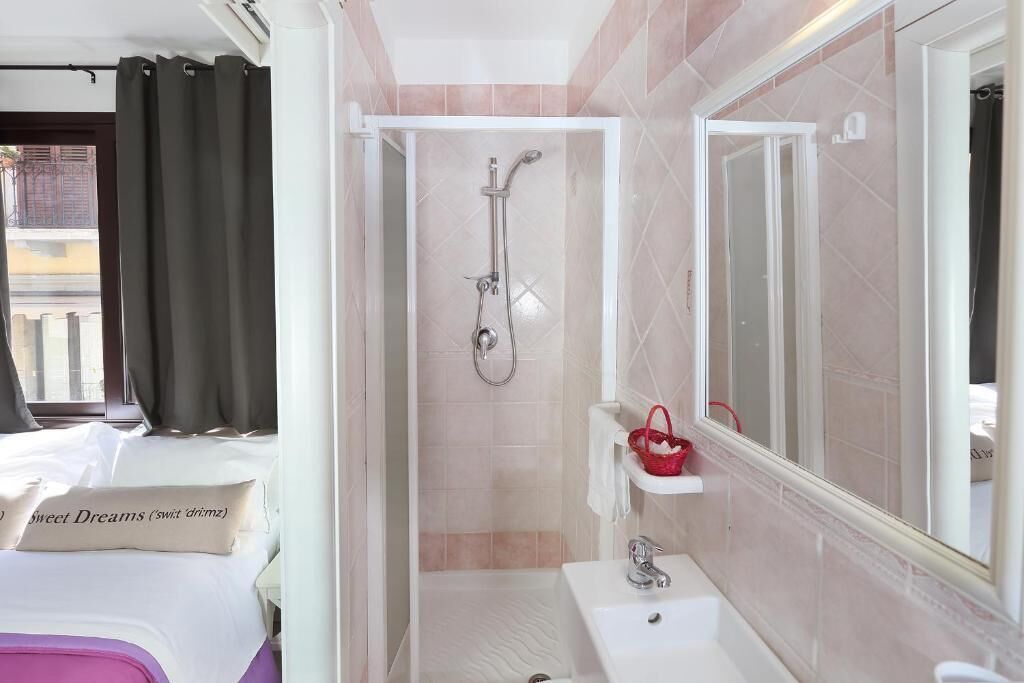 Ein Hotelzimmer mit Bett, Badezimmer mit Dusche, Waschbecken und Spiegel.