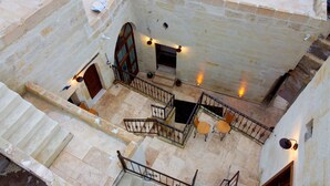 A courtyard with a staircase, a door, and a small seating area with a table and chairs. - Yesil Konak Cave Hotel (Ürgüp)