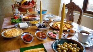 A dining table with various dishes, including olives, eggs, and bread. - Yesil Konak Cave Hotel (Ürgüp)
