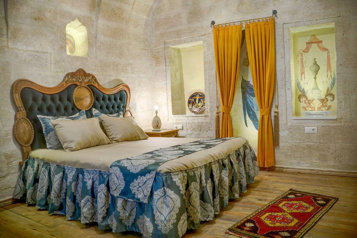 Un dormitorio con una cama grande, una mesita de noche, un espejo y una ventana con cortinas.