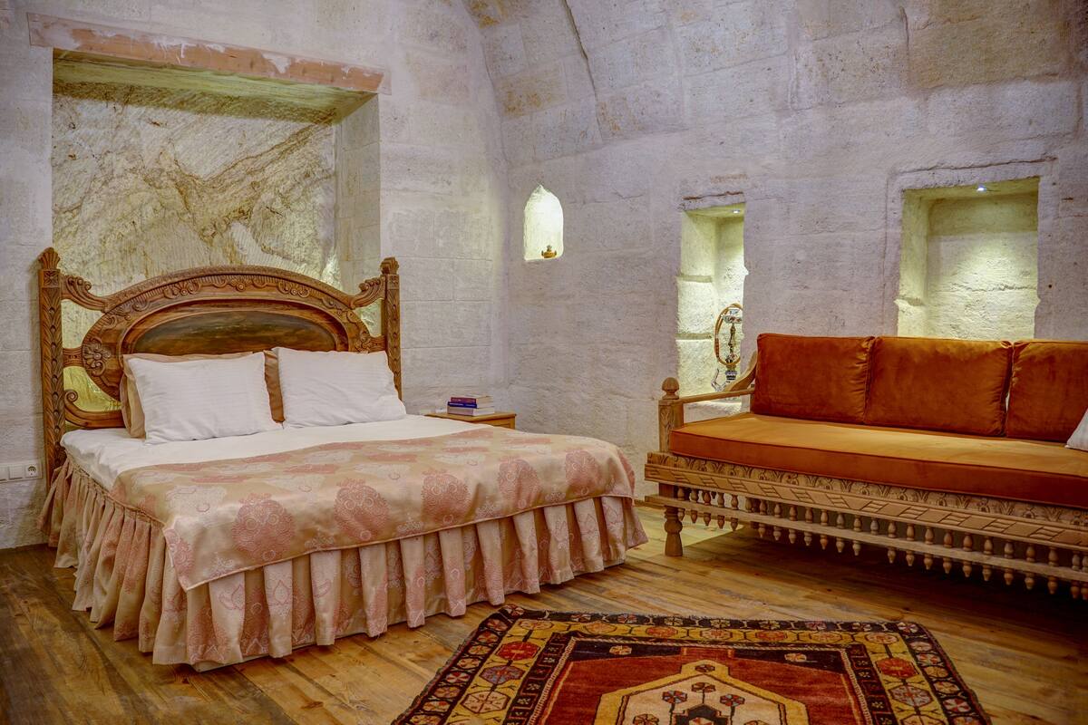 Un dormitorio con una cama de madera, un sofá y un tapete estampado.