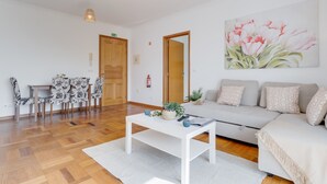 A modern living room with a sofa, a coffee table, and a dining area with chairs and a table. - Camara de Lobos Apartment (Camara de Lobos)