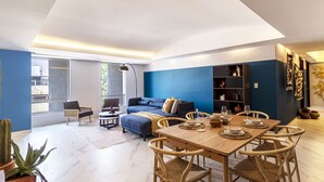Una sala moderna con una pared azul de acento, un sofá, una mesa de comedor para cuatro personas y una estantería.