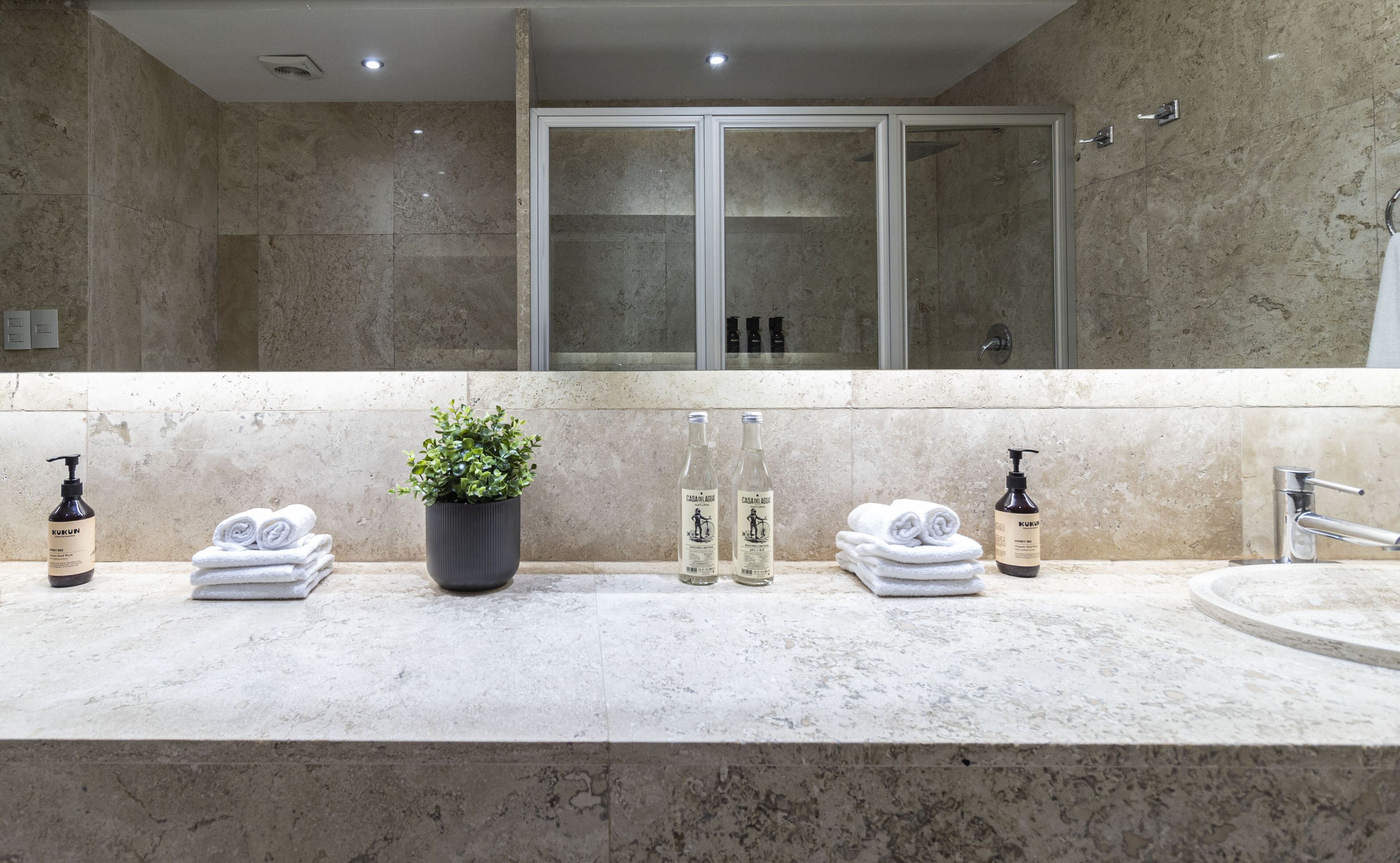 A bathroom with a marble countertop, a potted plant, and toiletries.