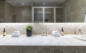 A bathroom with a marble countertop, a potted plant, and toiletries.