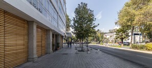 A sidewalk with a building featuring large windows and a sloped roof.