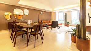 Una sala de estar moderna con comedor, que presenta un cactus grande, un sofá y una mesa de comedor con sillas.