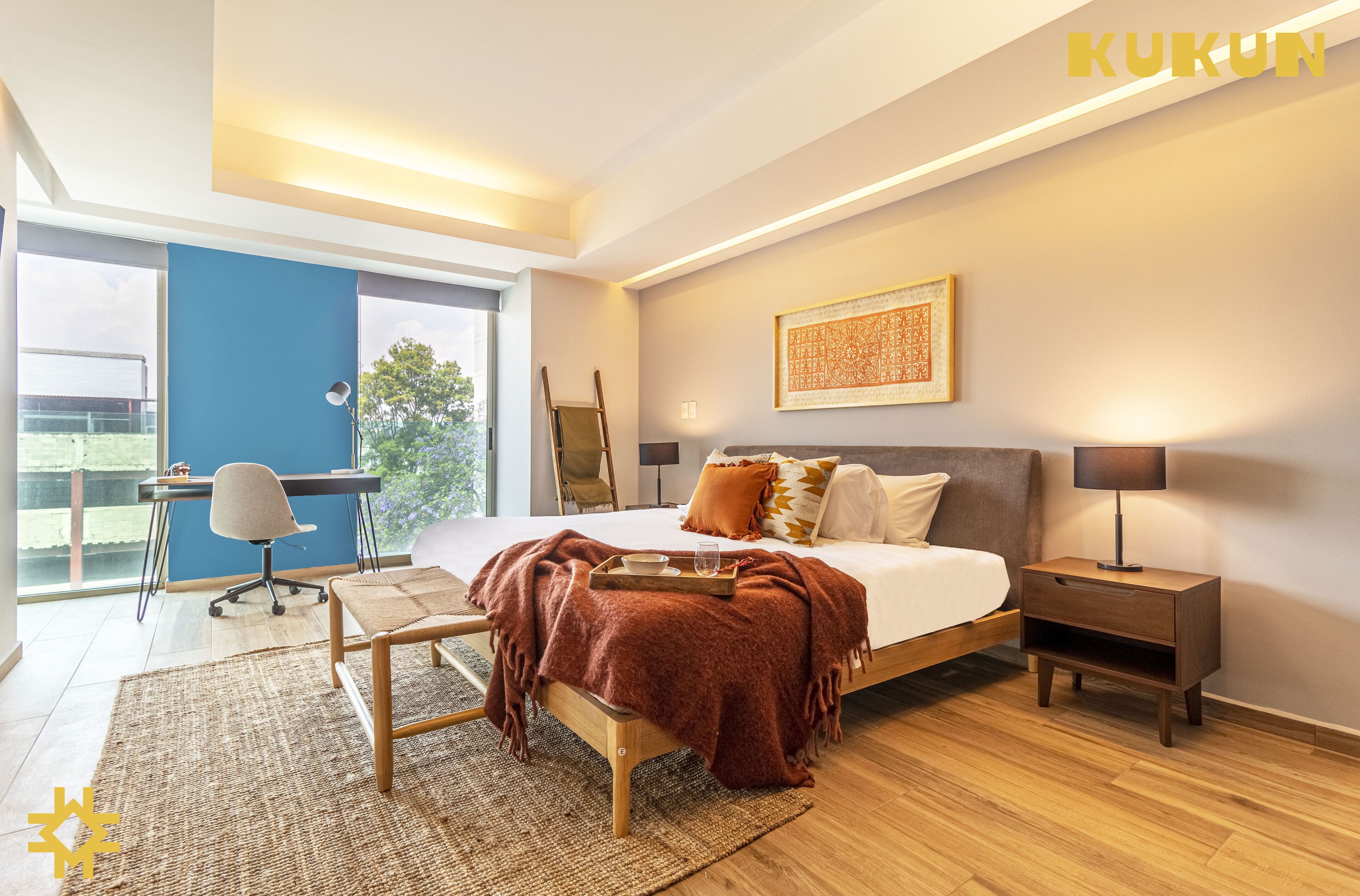 A modern bedroom with a large bed, bedside tables, a desk, and a chair.