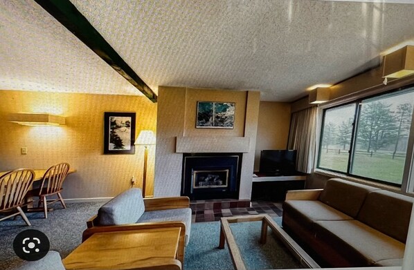 A living room with a fireplace, a television, and a large window.