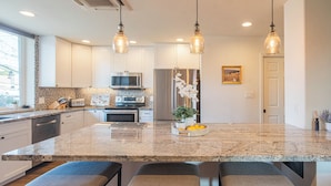 A modern kitchen with granite countertops, stainless steel appliances, and pendant lighting. - Nomad Gamer Pad- A Mountain Reserve Home w/ Pool, Spa, Esports Arena & Squat Gym (Phoenix)