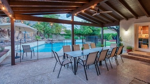 An outdoor patio with a pool, covered seating, and a ceiling fan. - Nomad Gamer Pad- A Mountain Reserve Home w/ Pool, Spa, Esports Arena & Squat Gym (Phoenix)