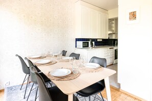 A dining area with a wooden table set for six, surrounded by black chairs. - 2ndhomes 2BR Center Apartment w Balcony (Helsinki)