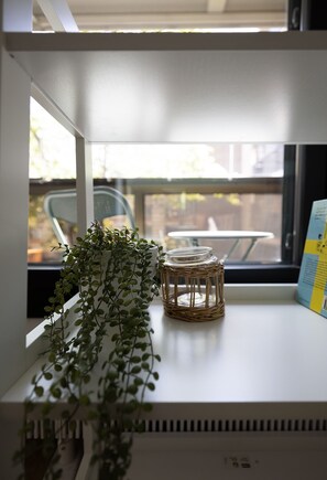 A shelf with a potted plant, a wicker container, and a book. - 2ndhomes 2BR Center Apartment w Balcony (Helsinki)