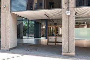 A building entrance with a glass door, a number '25' sign, and a covered area with a metal roof. - 2ndhomes 2BR Center Apartment w Balcony (Helsinki)
