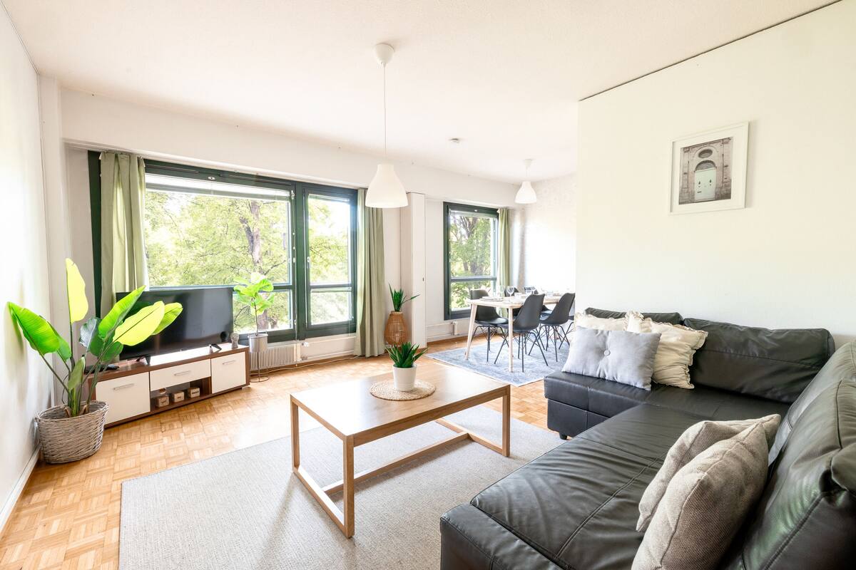 A modern living room with a sofa, TV, and dining area.