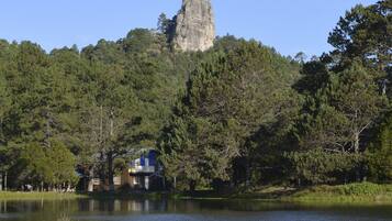Una casa junto a un lago, con una formación rocosa destacada al fondo.
