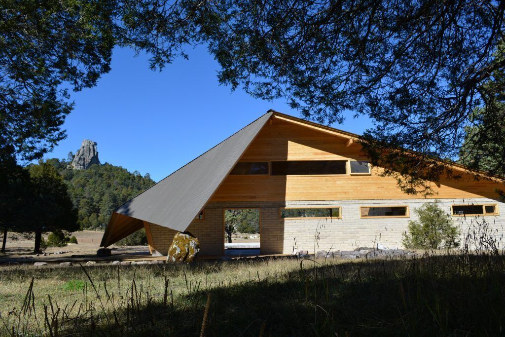 Un edificio moderno con techo inclinado, amplios ventanales y vistas a un paisaje natural.