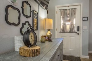 Un pasillo con un banco de madera, un reloj de pared, una lámpara y espejos enmarcados.