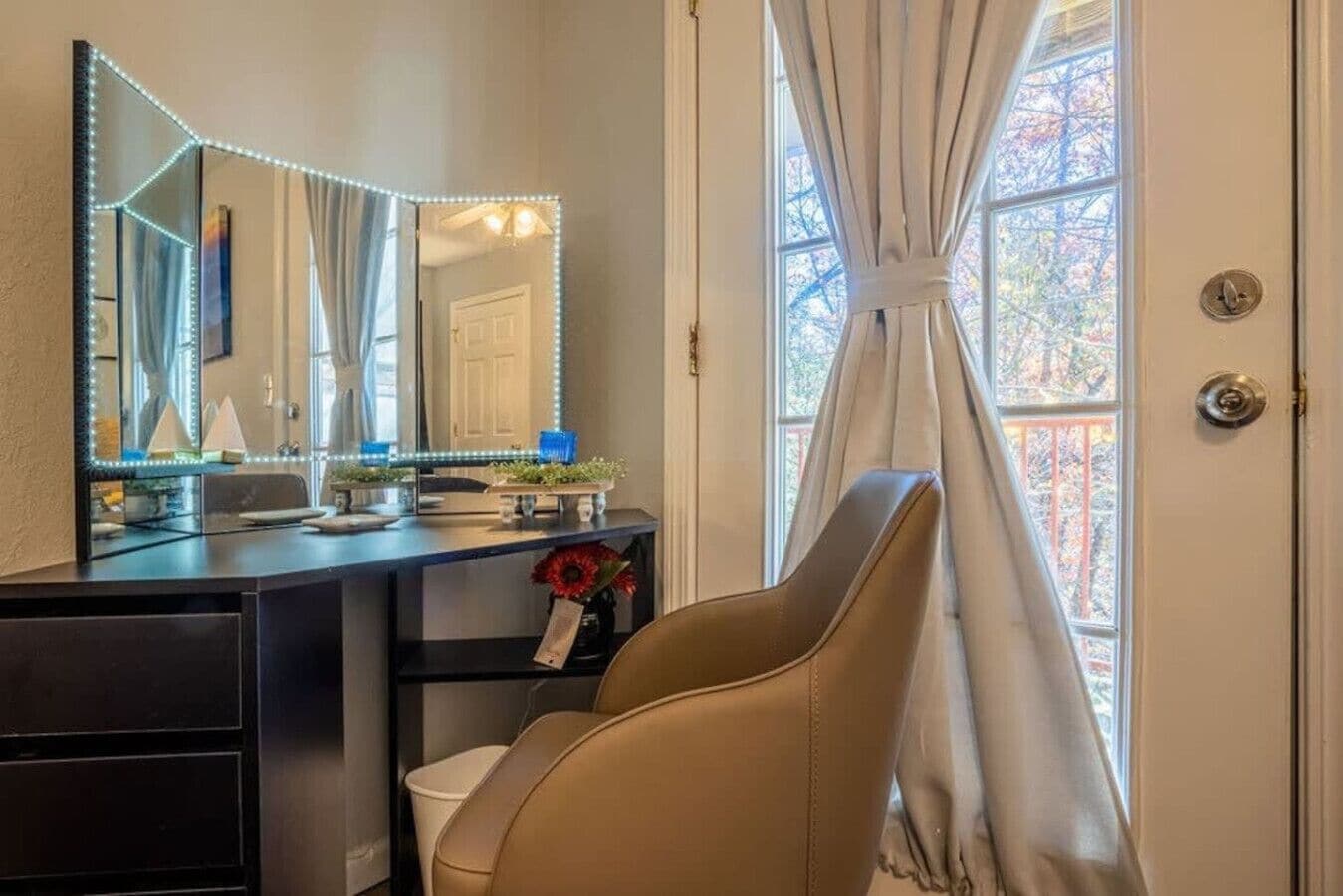 Een badkamer met een wastafel, spiegel en raam met gordijnen.