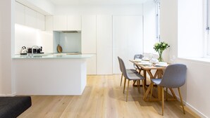 Een moderne keuken met witte kasten, een glazen eiland en een eetgedeelte met houten stoelen en een tafel.