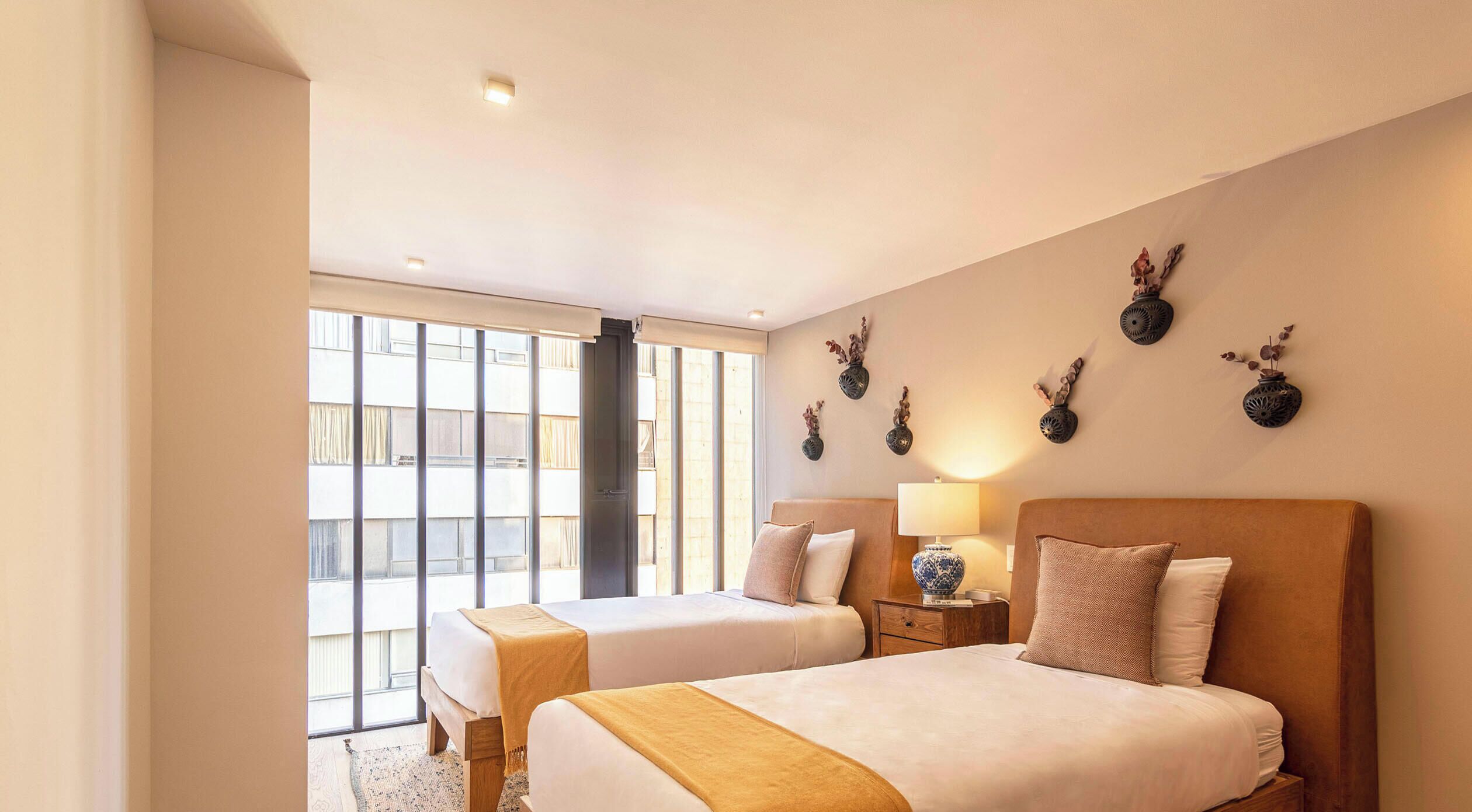 Una camera d'albergo con due letti, una grande finestra e decorazioni alle pareti.