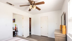 Un dormitorio con cama, ventilador de techo, cómoda y espejo.