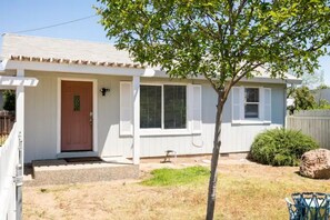 Une maison de plain-pied avec un porche à l’avant, une porte et une fenêtre avec des volets.
