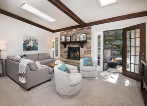 A living room with a stone fireplace, a sofa, two armchairs, and a coffee table. - Gorgeous Renovated Condo, Private Hot Tub, on Bus Route (Vail)