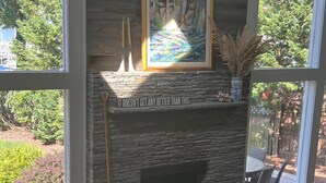 Uma sala de estar moderna com lareira de pedra, uma janela grande e vista para o exterior.