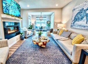 A living room with a fireplace, sofa, coffee table, and artwork.