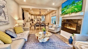 A living room with a fireplace, a dining area, and a kitchen in the background. - Bayside * 20008 * NEW Luxury Home * 5 BR *4.5 Bath (Selbyville)