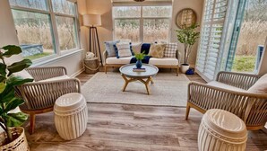 A cozy living room with a sofa, chairs, a coffee table, and large windows. - Bayside * 20008 * NEW Luxury Home * 5 BR *4.5 Bath (Selbyville)