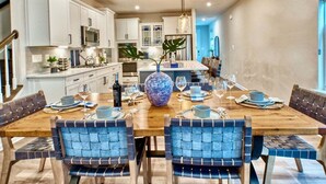 A dining area with a wooden table set for six, surrounded by blue upholstered chairs. - Bayside * 20008 * NEW Luxury Home * 5 BR *4.5 Bath (Selbyville)