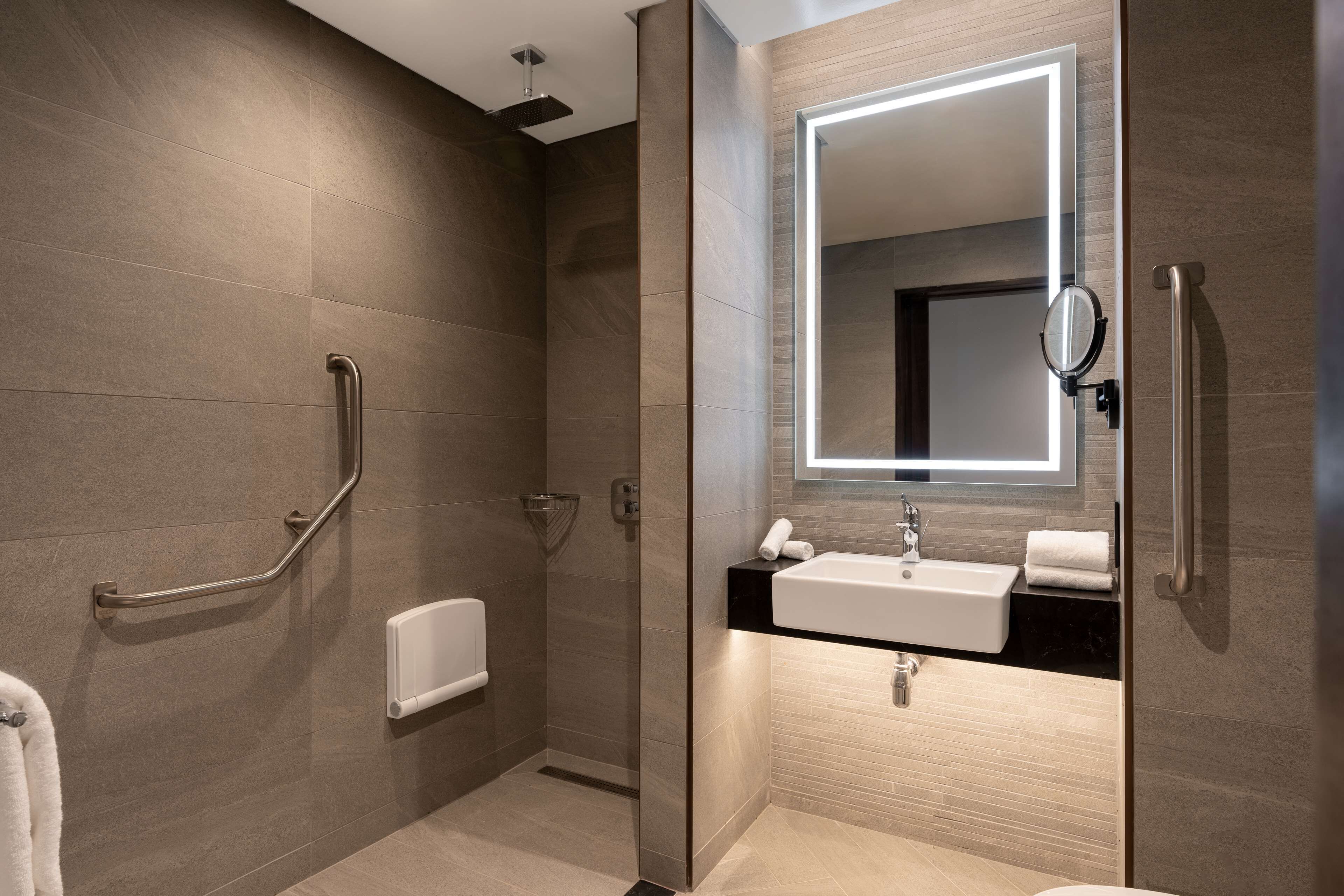 Un baño moderno con cabina de ducha, inodoro integrado y tocador con espejo.