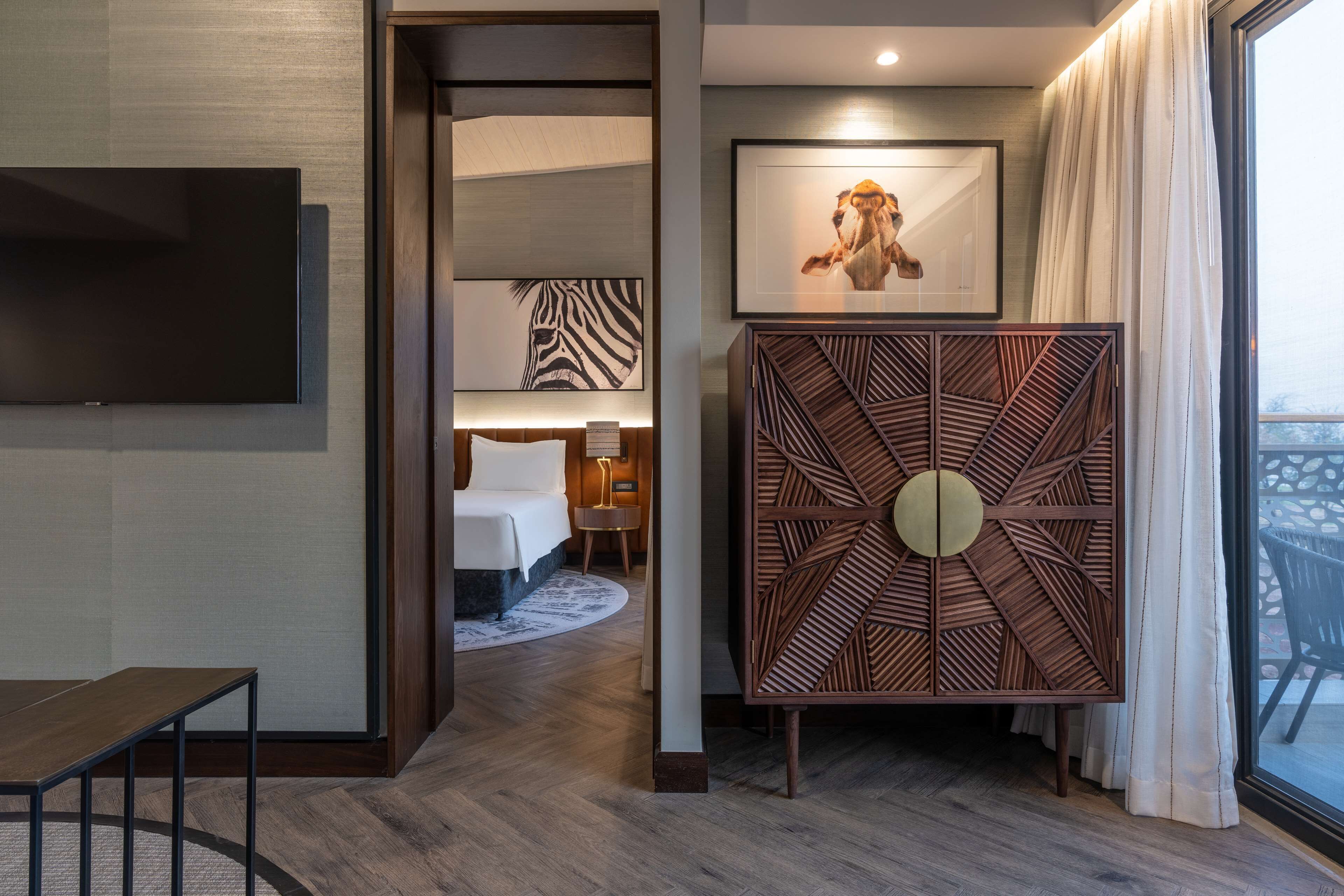 Une chambre d’hôtel avec un lit, une télévision, un panneau décoratif et un tableau encadré au mur.