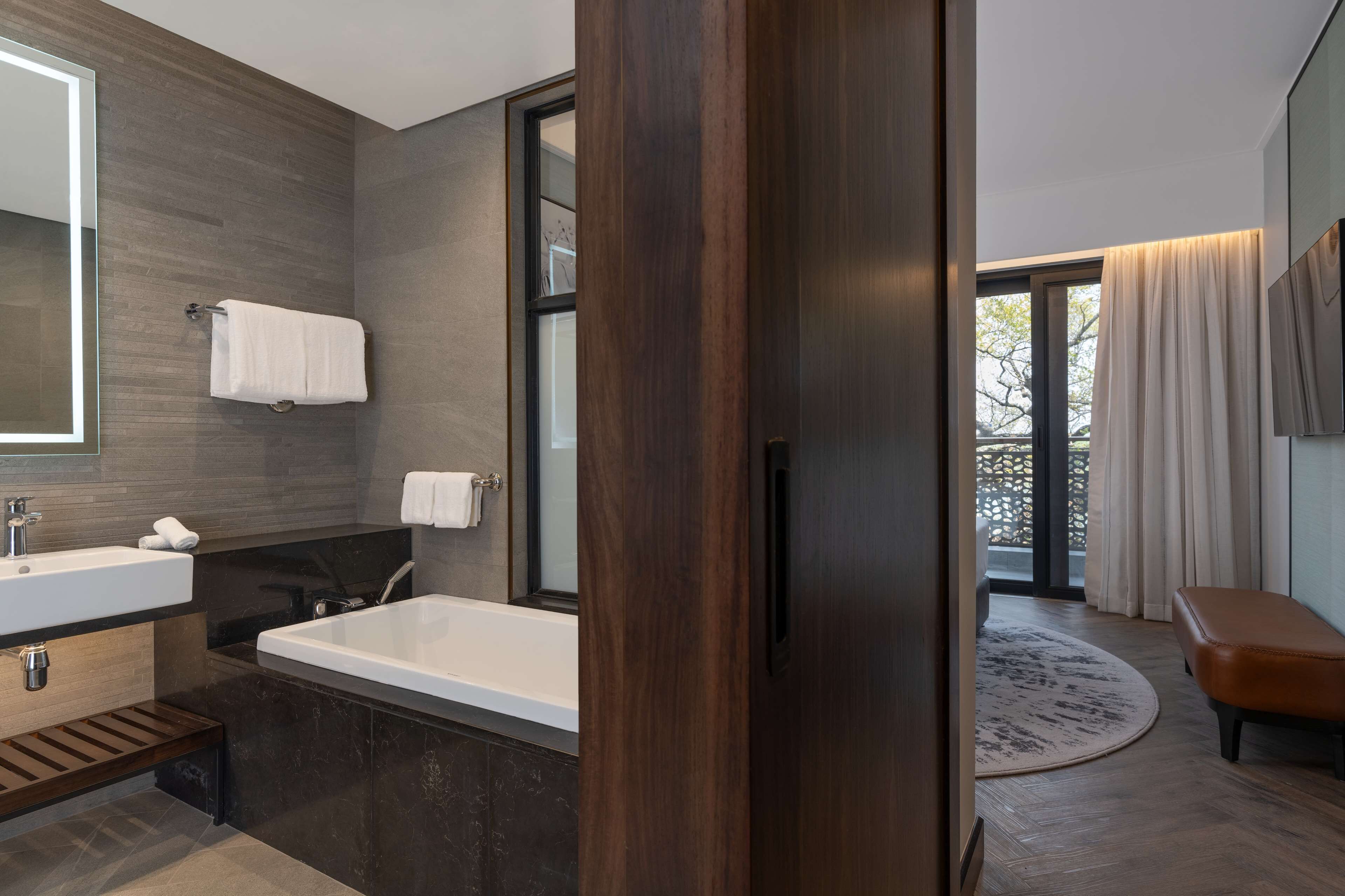 Un baño moderno con una bañera grande, un tocador con espejo y un perchero para toallas.