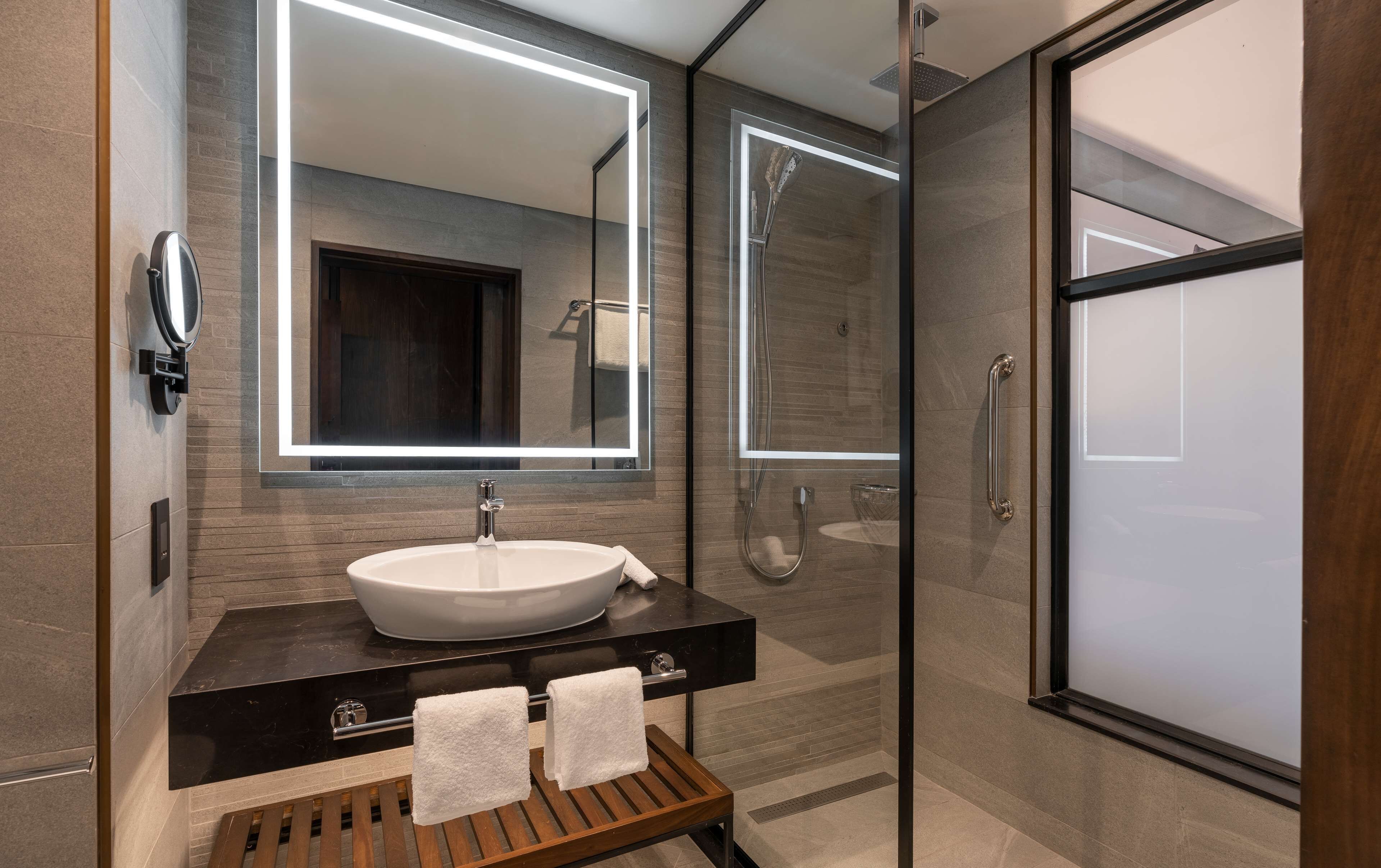 Une salle de bain moderne avec un grand miroir, un lavabo et une douche.