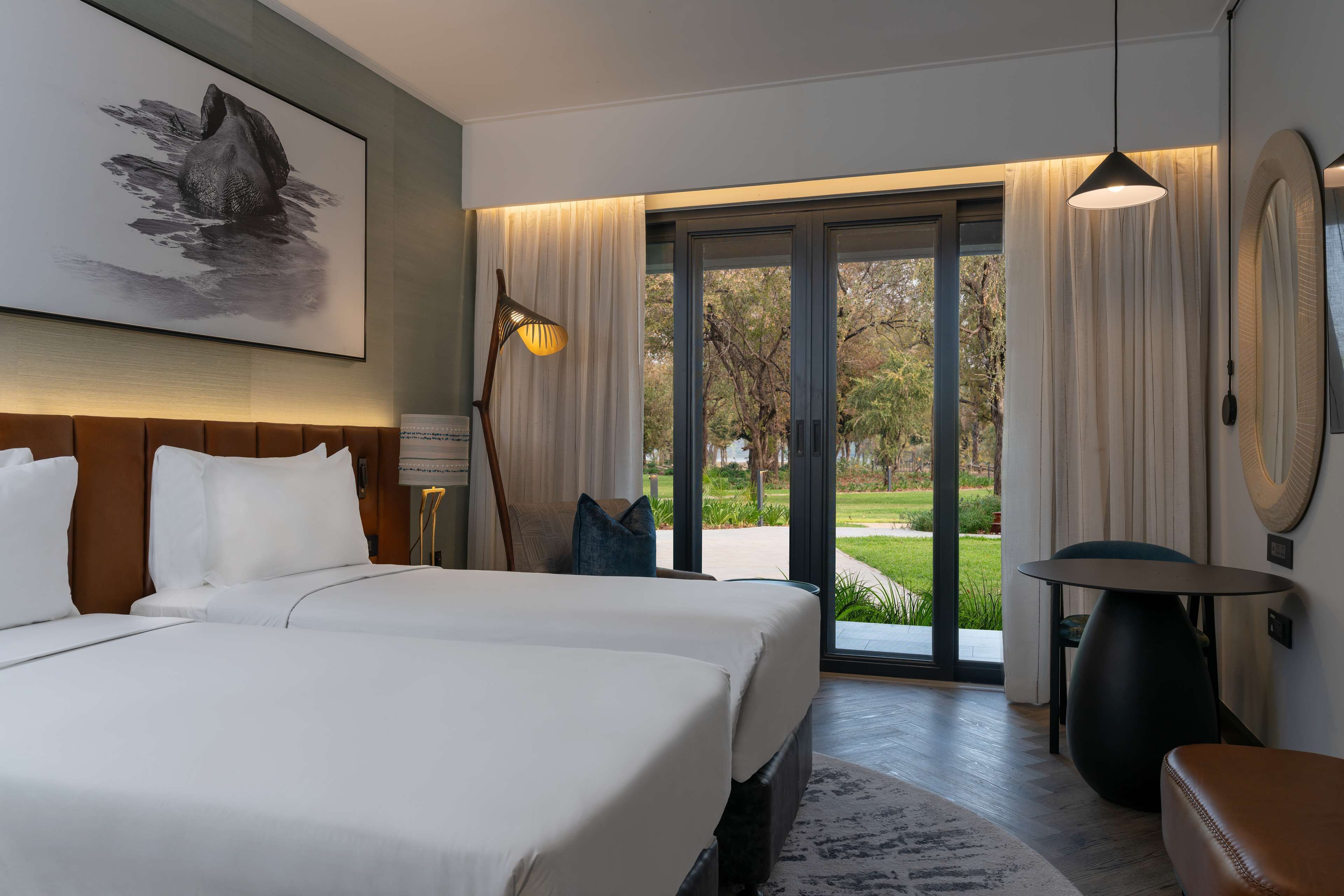 Habitación de hotel moderna con una cama grande, un escritorio y vistas al exterior.