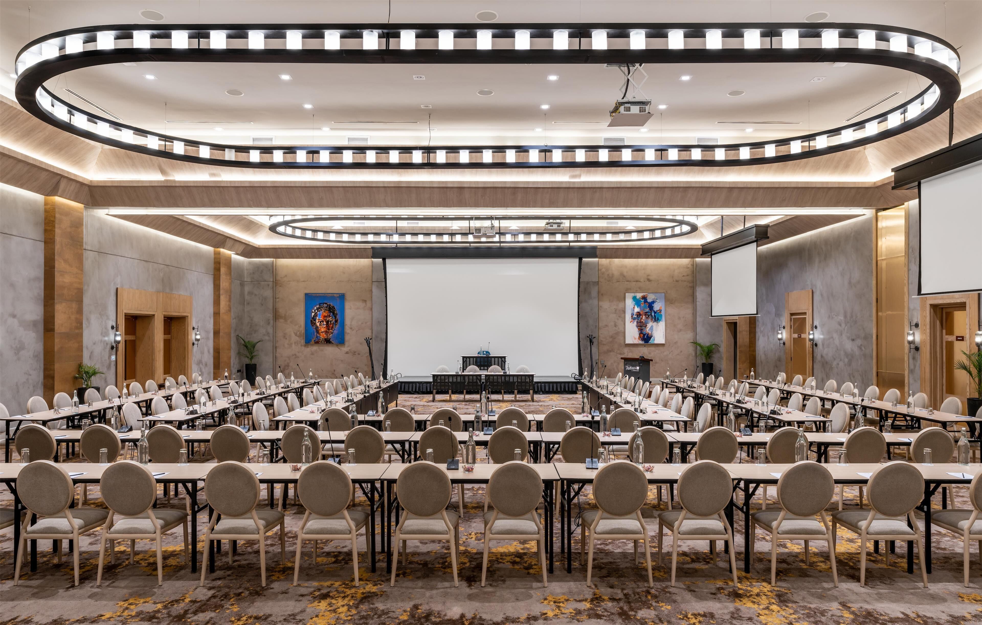A conference room with a long table, chairs, a podium, and a large screen.