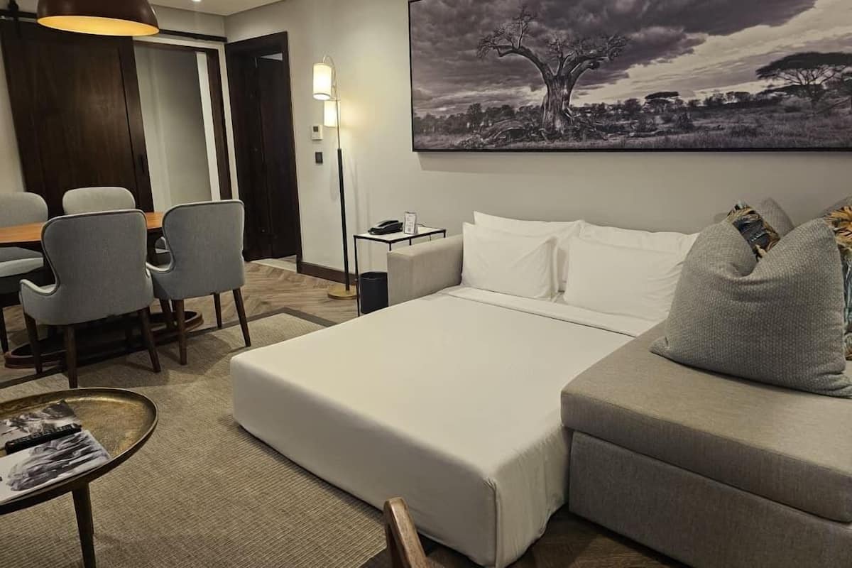 Une chambre d’hôtel avec un lit, un canapé, un bureau et des chaises.