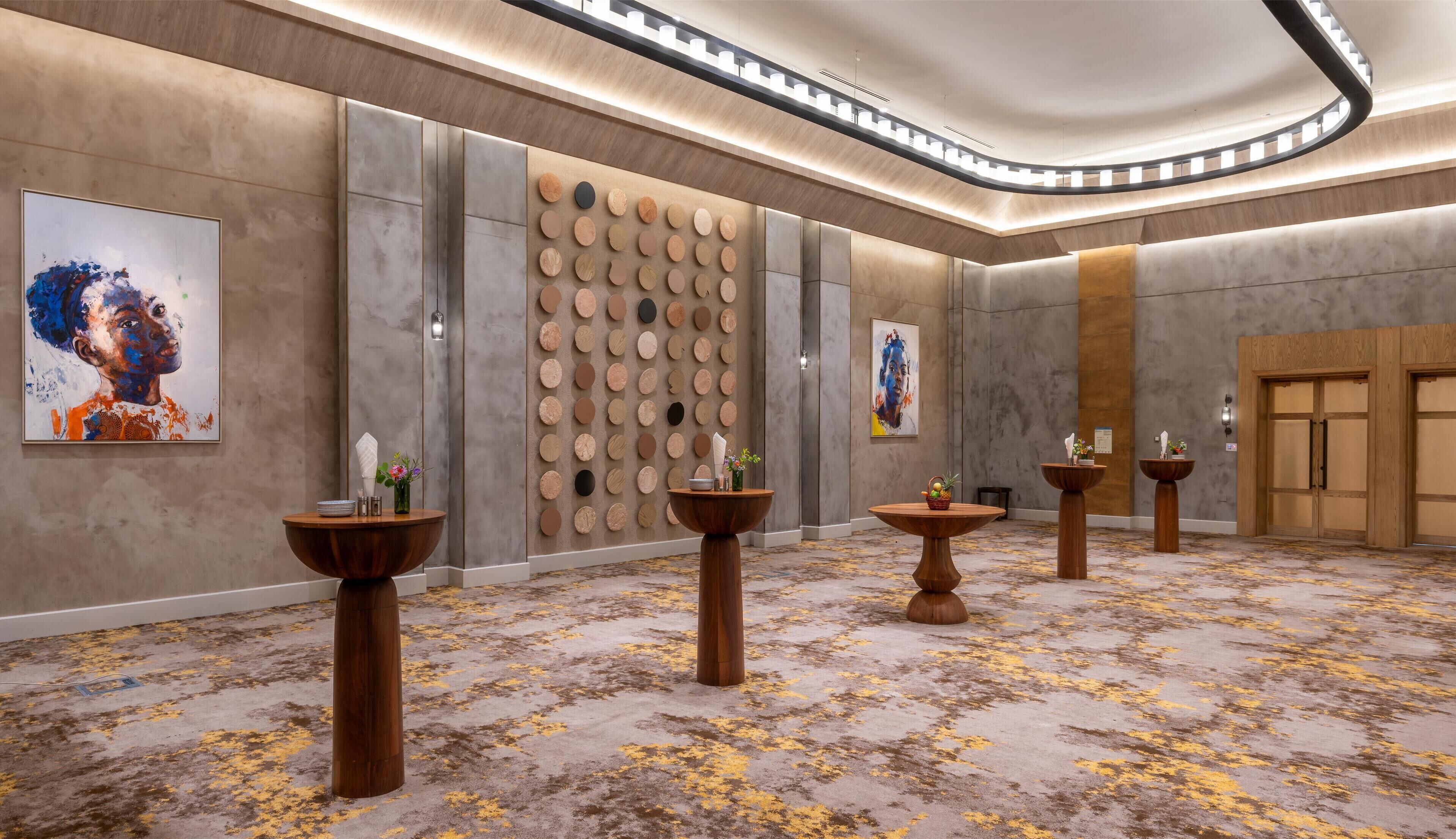 A modern hotel lobby with a marble floor, wooden columns, and a wall with circular patterns.