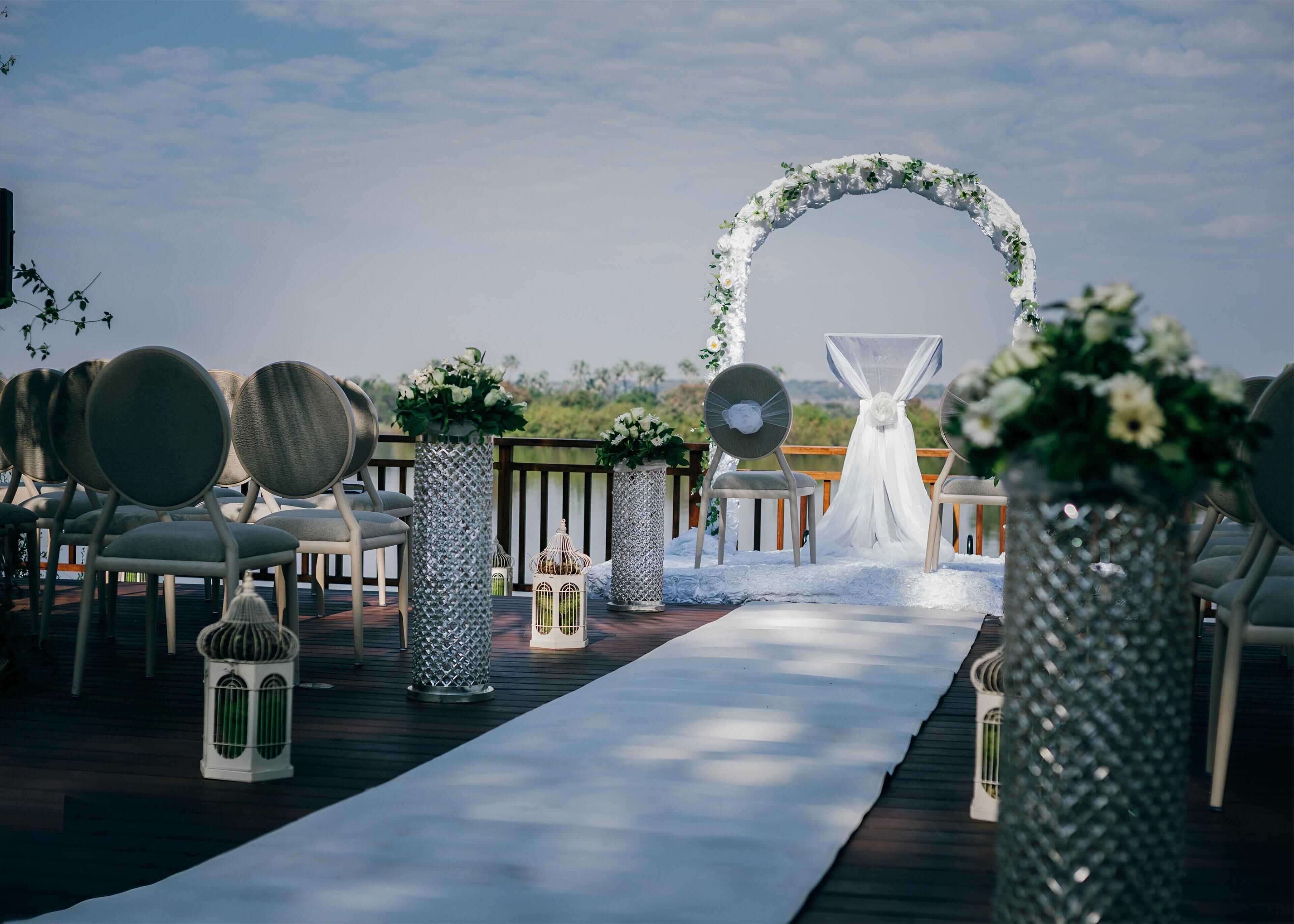 A wedding aisle with chairs and a floral arch.