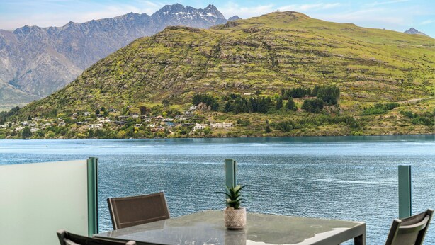 A table with chairs and a pineapple centerpiece, overlooking a lake with mountains in the background. - Frankton House - Queenstown Holiday Home (Queenstown)