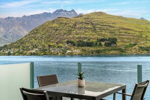 Een tafel met stoelen en een ananas als middelpunt, met uitzicht op een meer met bergen op de achtergrond.