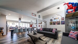 A modern living room with a grey sofa, a wooden coffee table, and a dining area with chairs and a table. - Avengers Campus: 🌊🎥🍿🕹Heated Pool, Theater, Arcade+ (Stanton)