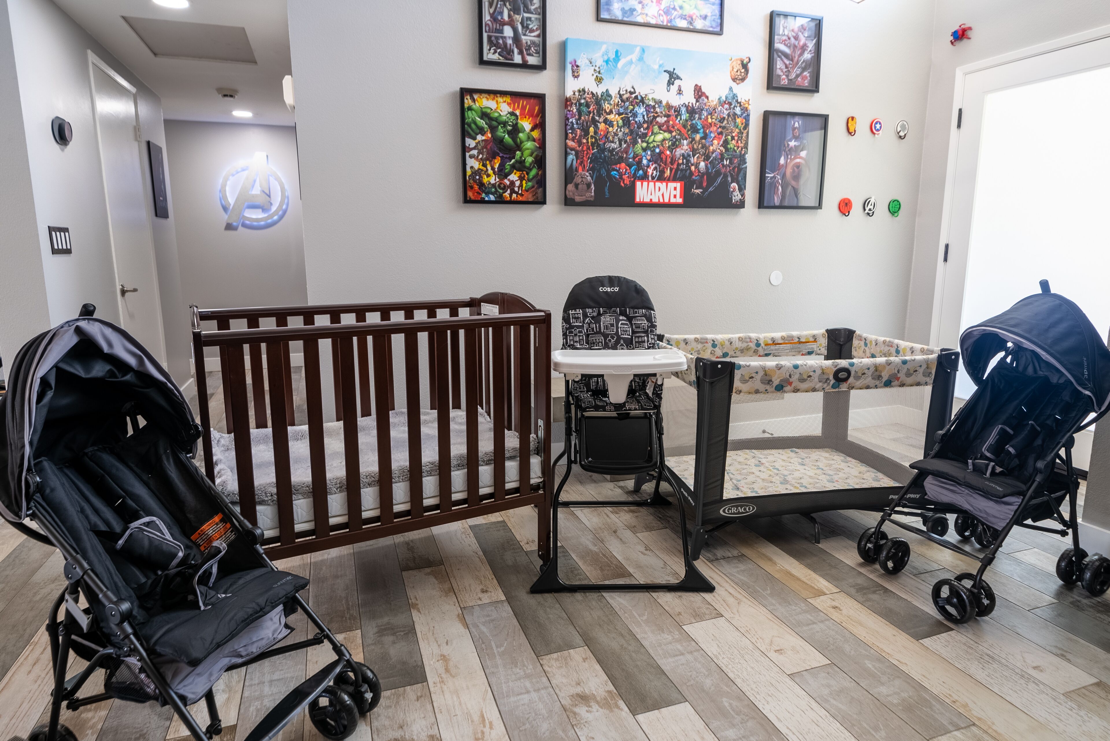 A baby room with a crib, changing table, and two strollers.