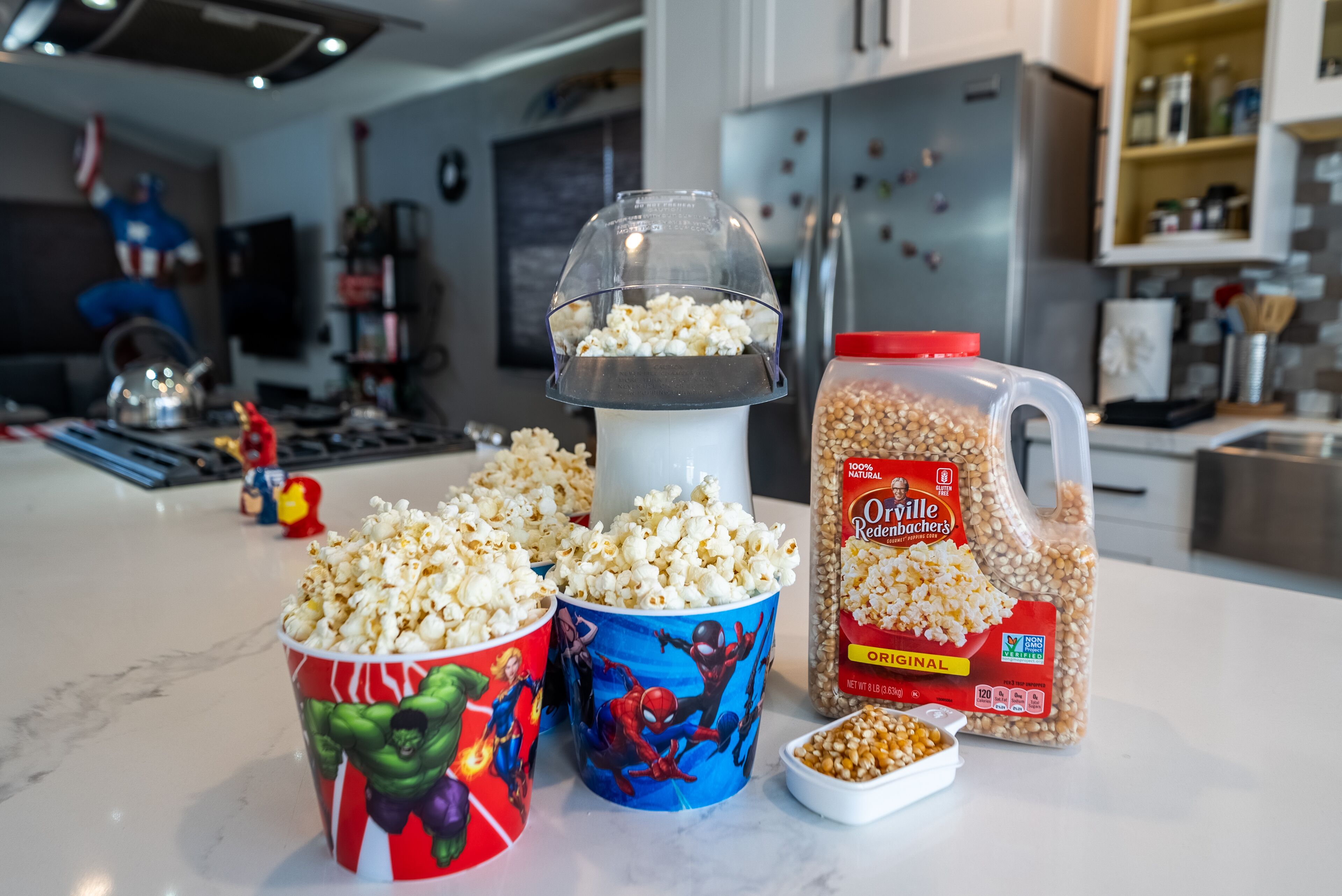 A kitchen counter with popcorn containers, a popcorn popper, and a bag of popcorn kernels.