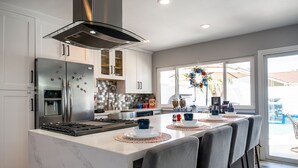 A modern kitchen with a large island, stainless steel appliances, and a view to the outdoors. - Avengers Campus: 🌊🎥🍿🕹Heated Pool, Theater, Arcade+ (Stanton)